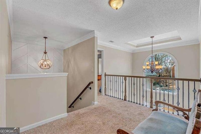 corridor with a notable chandelier, carpet flooring, an upstairs landing, a raised ceiling, and crown molding