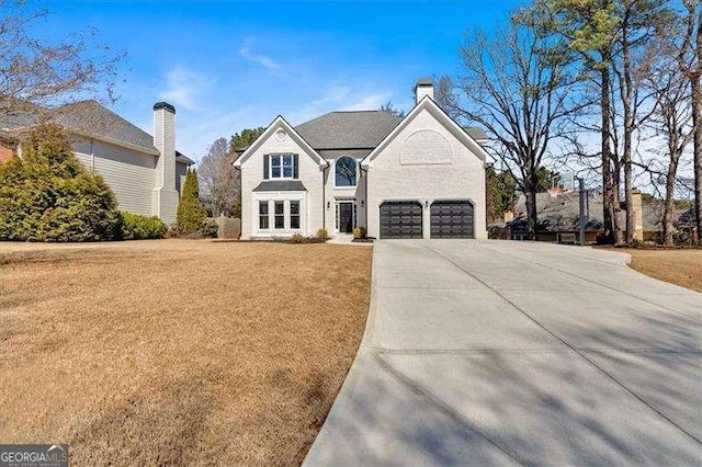 view of front of home featuring a garage, driveway, a chimney, and a front lawn