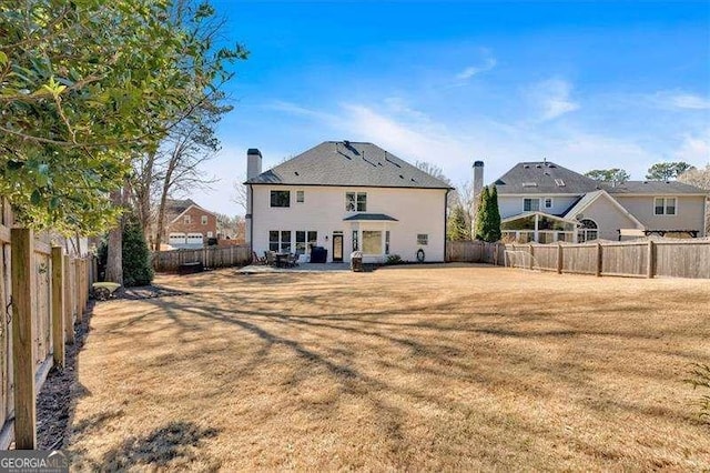 rear view of house with a fenced backyard and a lawn