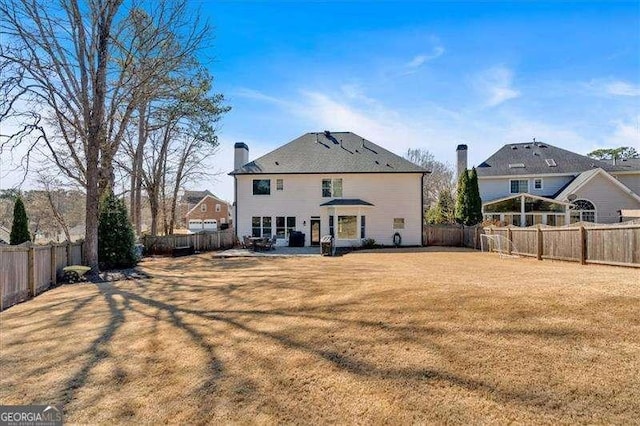 rear view of property with a yard, a patio, a chimney, and a fenced backyard