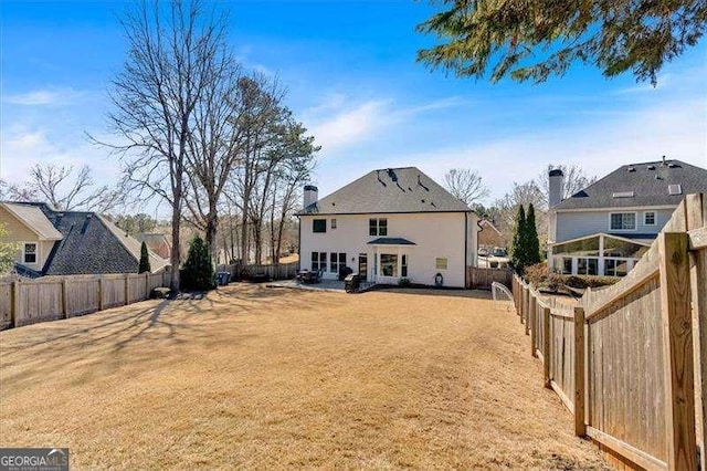 back of house with a fenced backyard and a yard