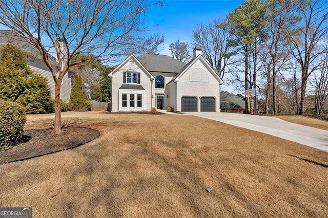 view of front facade with a front yard, driveway, a chimney, and an attached garage