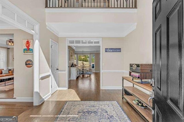 foyer entrance with ornamental molding, baseboards, and wood finished floors