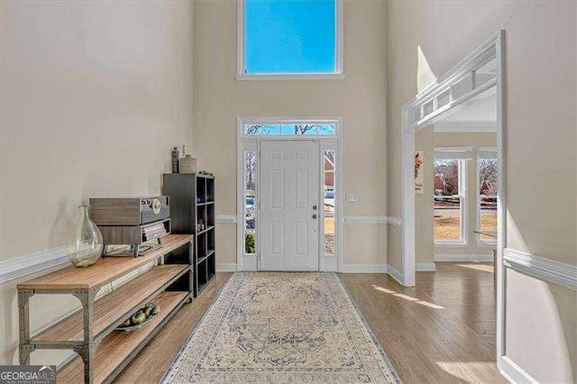 entryway with a high ceiling, baseboards, and wood finished floors