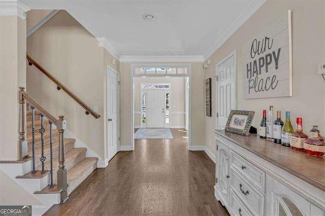 foyer entrance featuring dark wood finished floors, crown molding, a dry bar, baseboards, and stairs