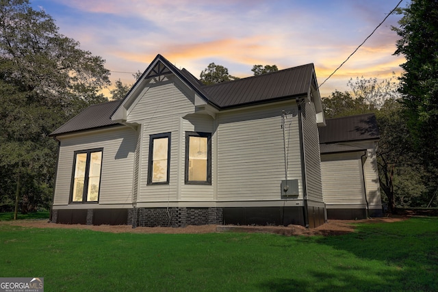 view of side of home featuring metal roof and a lawn