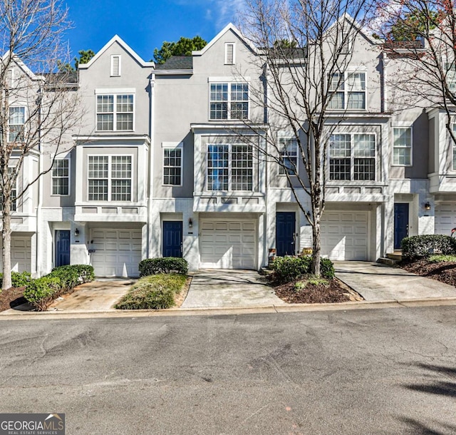 townhome / multi-family property featuring a garage, concrete driveway, and stucco siding