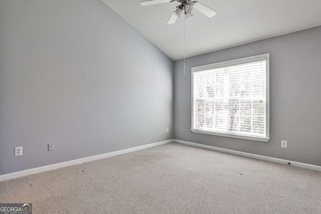 carpeted spare room featuring lofted ceiling, baseboards, and a ceiling fan