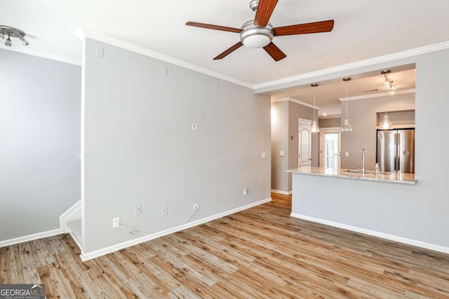 unfurnished living room featuring crown molding, a sink, wood finished floors, and baseboards