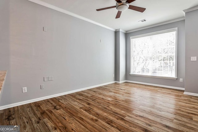 unfurnished room featuring visible vents, ornamental molding, a ceiling fan, wood finished floors, and baseboards