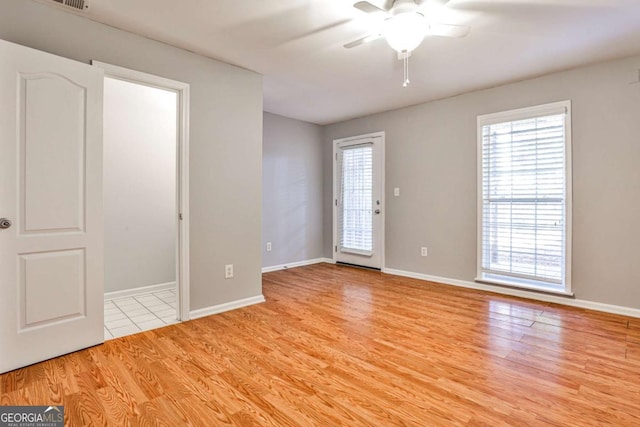 spare room featuring ceiling fan, visible vents, baseboards, and wood finished floors