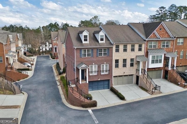 view of front of home with an attached garage, brick siding, driveway, stairway, and a residential view