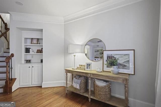 interior space with baseboards, stairway, wood finished floors, and ornamental molding