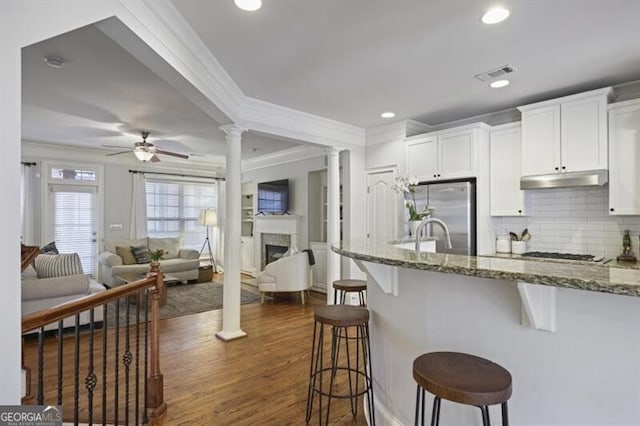 kitchen with stone counters, a breakfast bar, decorative columns, visible vents, and freestanding refrigerator