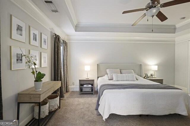 bedroom featuring carpet floors, visible vents, a ceiling fan, ornamental molding, and a tray ceiling