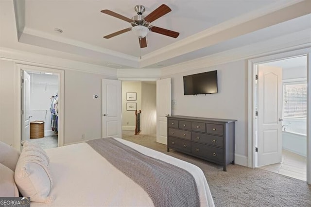 carpeted bedroom featuring ornamental molding, a raised ceiling, a spacious closet, and ensuite bath