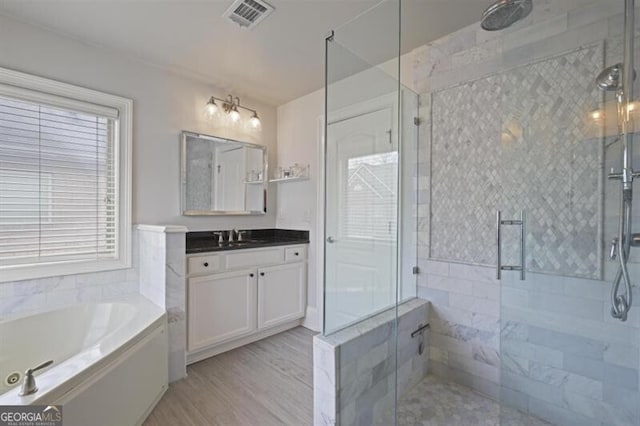 full bath featuring wood finished floors, vanity, visible vents, a whirlpool tub, and a stall shower