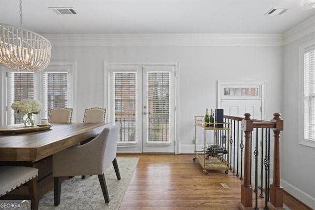 dining room featuring an inviting chandelier, visible vents, wood finished floors, and french doors