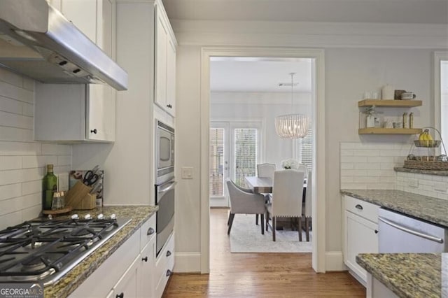 kitchen with stone counters, under cabinet range hood, white cabinets, appliances with stainless steel finishes, and light wood-type flooring