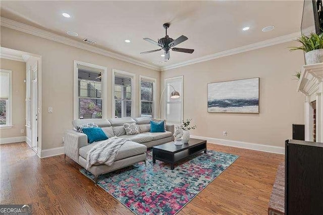 living room with baseboards, visible vents, crown molding, and wood finished floors