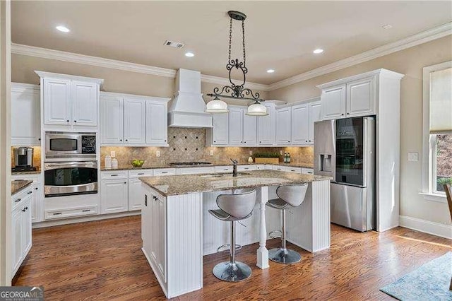 kitchen featuring premium range hood, a sink, visible vents, white cabinetry, and appliances with stainless steel finishes