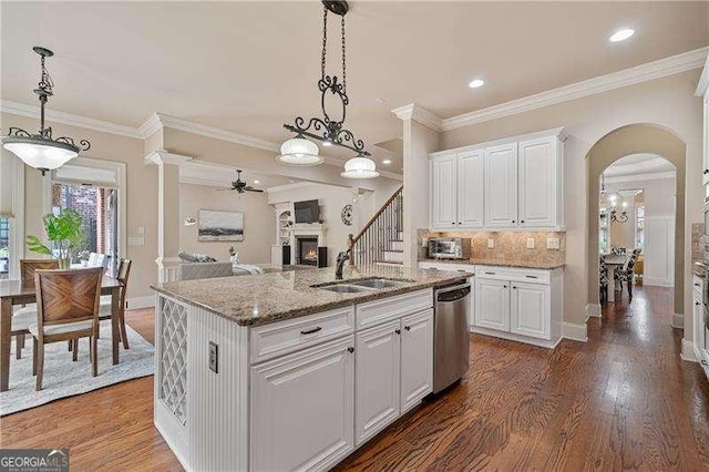 kitchen featuring a warm lit fireplace, arched walkways, dark wood-type flooring, a sink, and stainless steel dishwasher