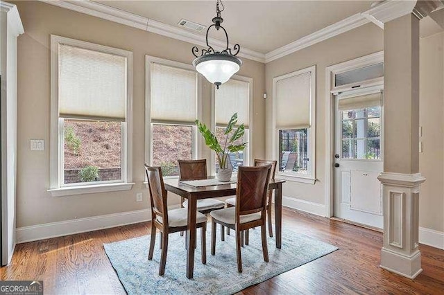 dining room with decorative columns, baseboards, visible vents, wood finished floors, and crown molding