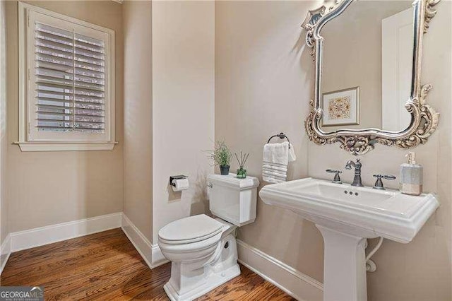 bathroom with toilet, baseboards, and wood finished floors