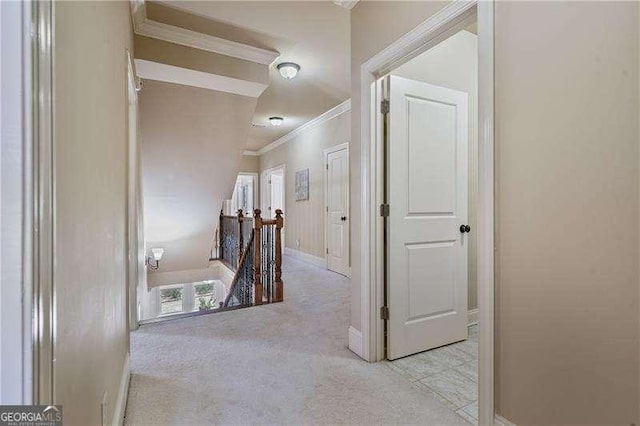 hall featuring carpet, ornamental molding, baseboards, and an upstairs landing