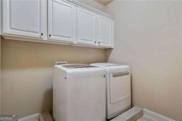 washroom with washer and clothes dryer, cabinet space, and baseboards