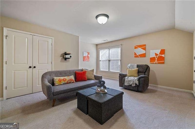 carpeted living area with lofted ceiling and baseboards