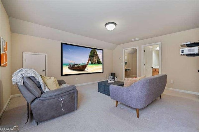 home theater room featuring light colored carpet, vaulted ceiling, and baseboards