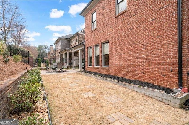 exterior space with brick siding, a patio area, and fence