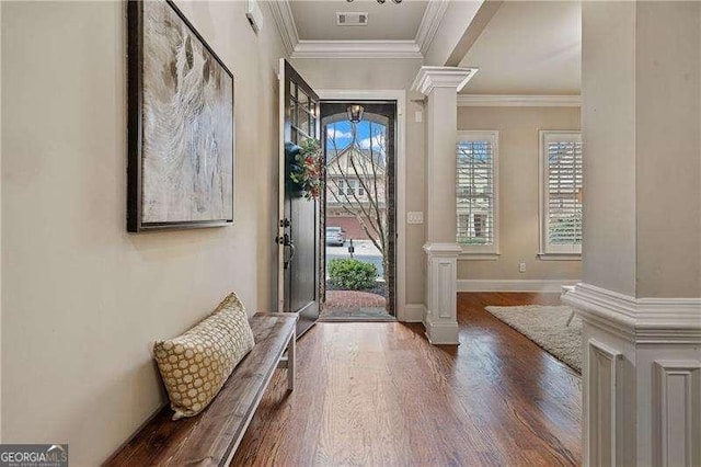 foyer with decorative columns, crown molding, visible vents, and wood finished floors