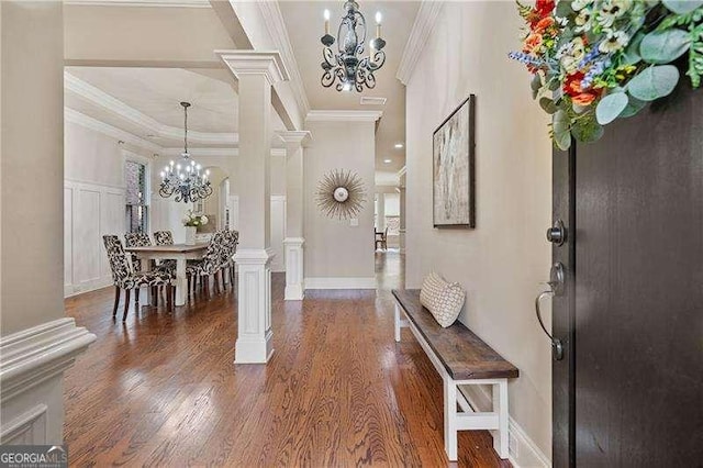 entryway with dark wood-style floors, crown molding, decorative columns, a decorative wall, and a chandelier