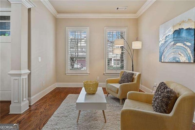 living area with ornamental molding, visible vents, decorative columns, and wood finished floors