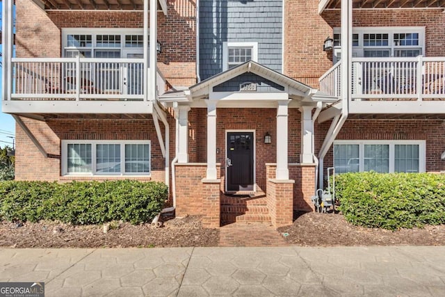 entrance to property with brick siding and a balcony