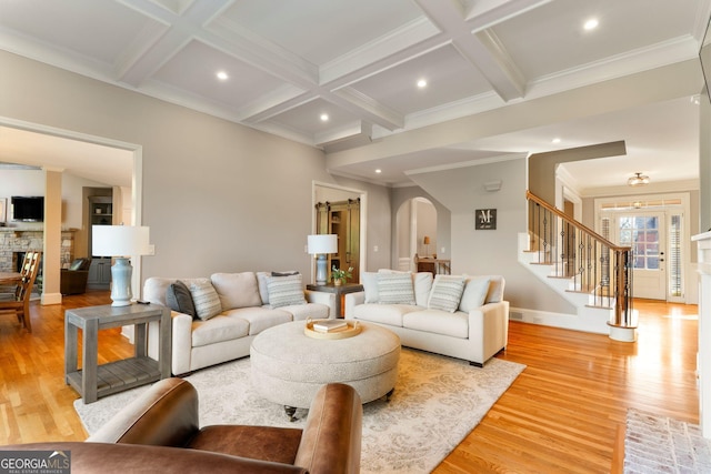 living area featuring stairway, arched walkways, coffered ceiling, and beam ceiling