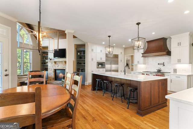 kitchen featuring light wood finished floors, built in appliances, custom exhaust hood, and light countertops