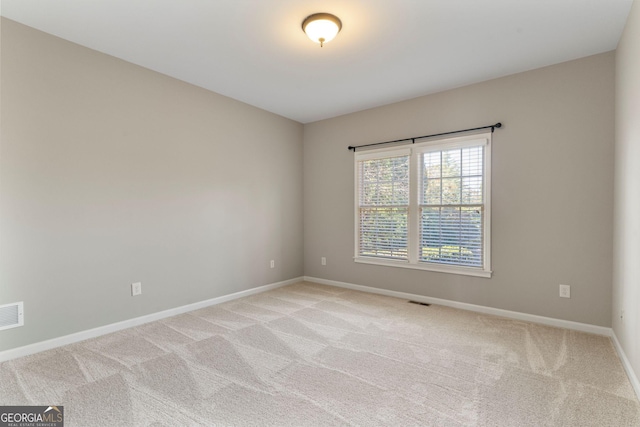 unfurnished room featuring visible vents, light colored carpet, and baseboards