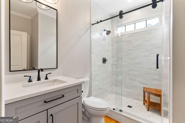 bathroom with vanity, toilet, a shower stall, and crown molding