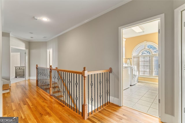 hall featuring wood finished floors, baseboards, washer / dryer, crown molding, and an upstairs landing