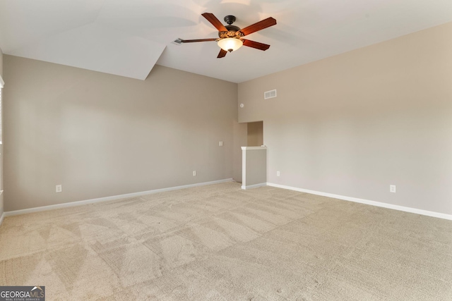 spare room with visible vents, ceiling fan, baseboards, vaulted ceiling, and light carpet