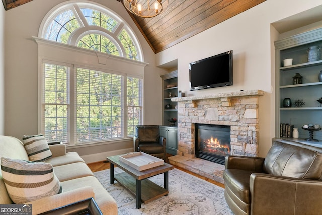 living area with built in features, wood ceiling, a wealth of natural light, a fireplace, and wood finished floors