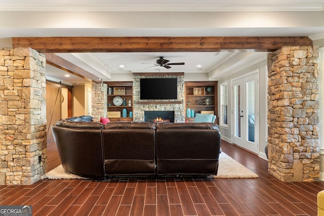 living area featuring crown molding, wood finish floors, a barn door, a stone fireplace, and a ceiling fan