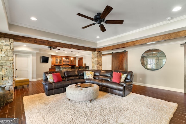 living room with wood finish floors, ornamental molding, a ceiling fan, a barn door, and baseboards