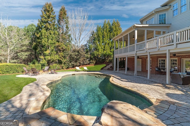 pool featuring a lawn, a ceiling fan, a patio, a fire pit, and a sunroom