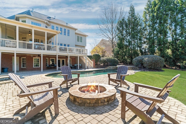 view of patio / terrace featuring an outdoor fire pit, an outdoor pool, ceiling fan, stairs, and french doors