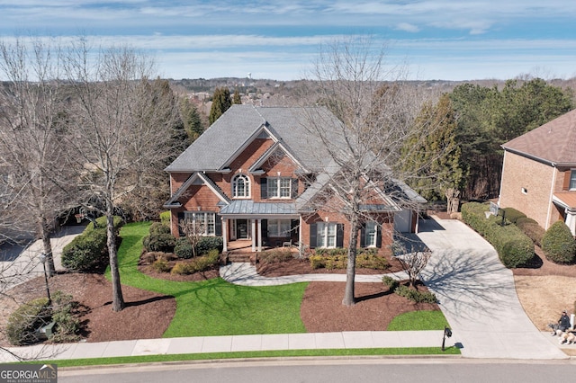 view of front of house with brick siding, a porch, a front yard, roof with shingles, and driveway