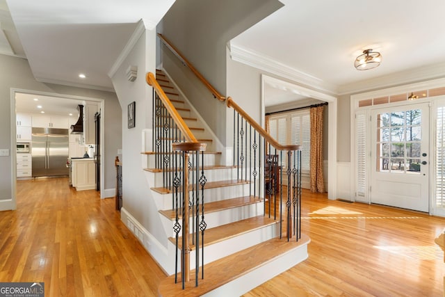 entryway with stairway, a wainscoted wall, recessed lighting, ornamental molding, and light wood-style floors